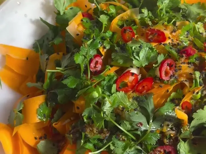 Carrot ribbon salad topped with cilantro, sliced red chili and black sesame seeds