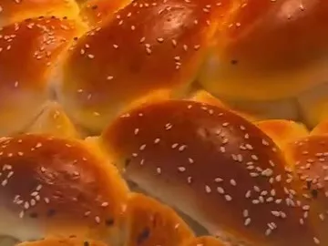 Golden baked challah buns topped with sesame seeds