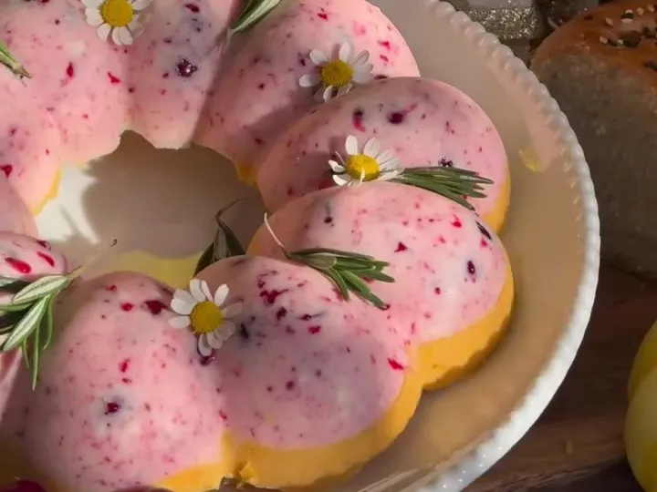 Pink and orange molded butter ring decorated with rosemary, cranberries and flowers
