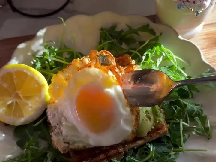 Crispy tofu waffle on arugula topped with a fried egg and chili crisp