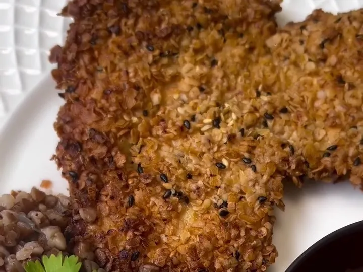 Oat-crusted chicken schnitzel on a plate with ketchup