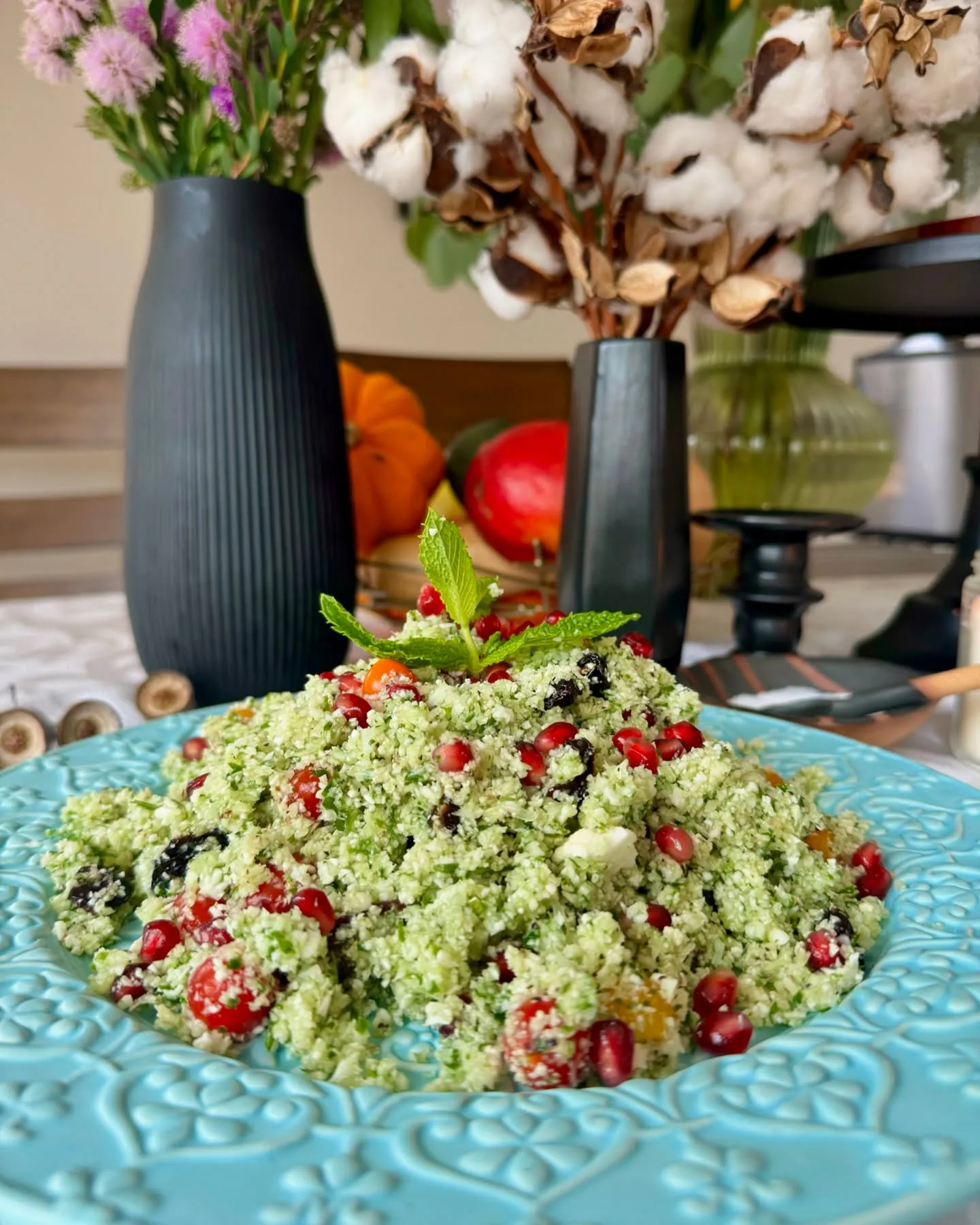 Cauliflower tabouli salad with herbs and pomegranate seeds on a turquoise plate