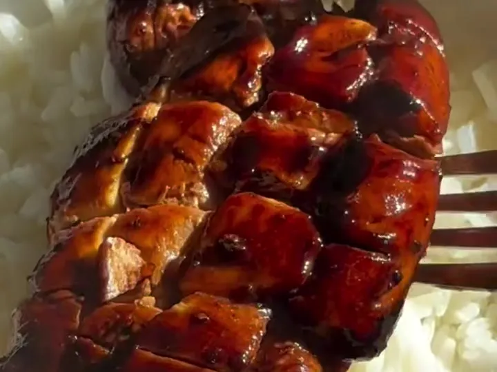 Scored chicken breast with a dark soy and honey glaze on white rice