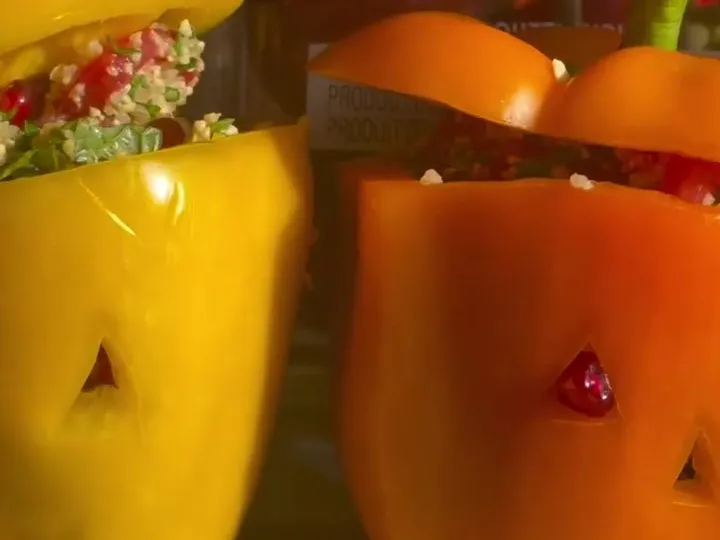 Mini bell peppers carved with jack-o’-lantern faces and stuffed with bulgur salad