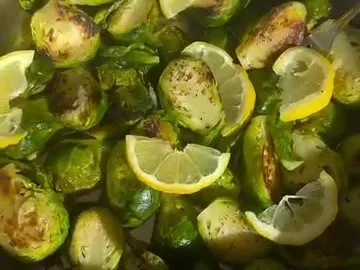 Pan-roasted Brussels sprout halves with lemon slices in a skillet