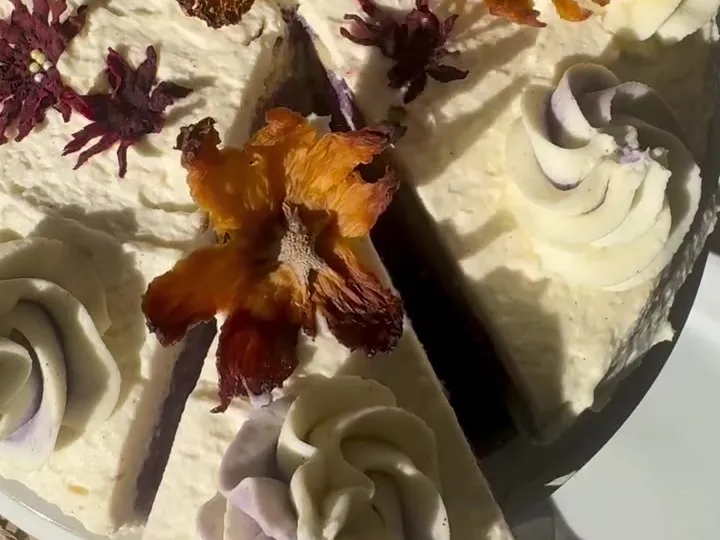 Pound cake covered in cream cheese topping with piped rosettes and pressed flowers