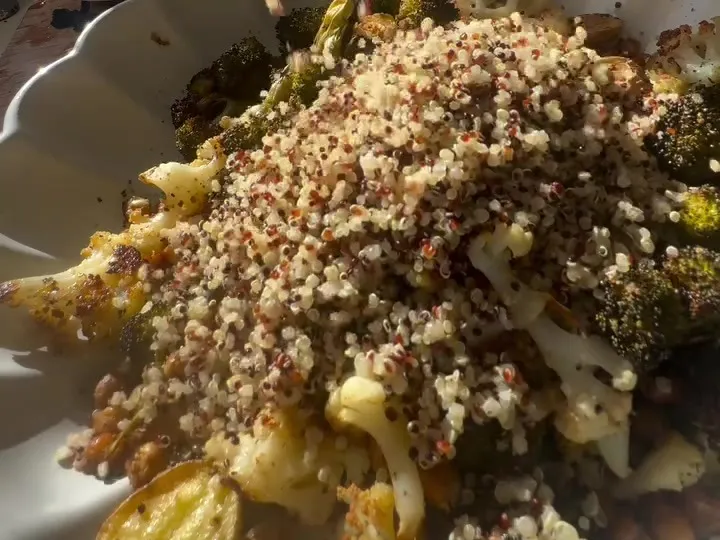 Cooked quinoa spooned over roasted vegetables on a plate