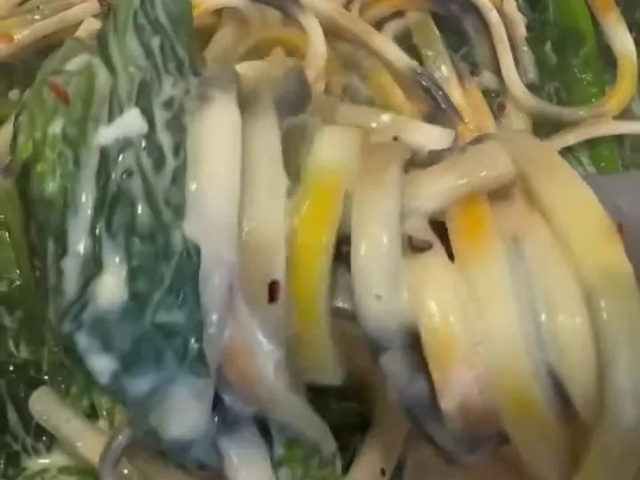 Striped pasta tossed with rapini in a creamy sauce in a pan