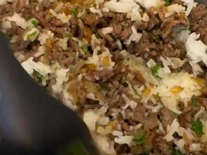 Rice mixed with browned ground beef and parsley in a pot