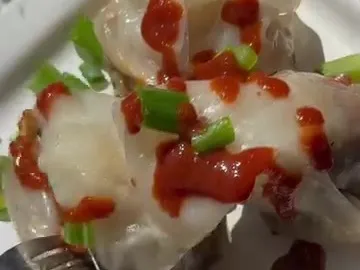 Rice paper kebab dumplings on a plate with sriracha and green onions