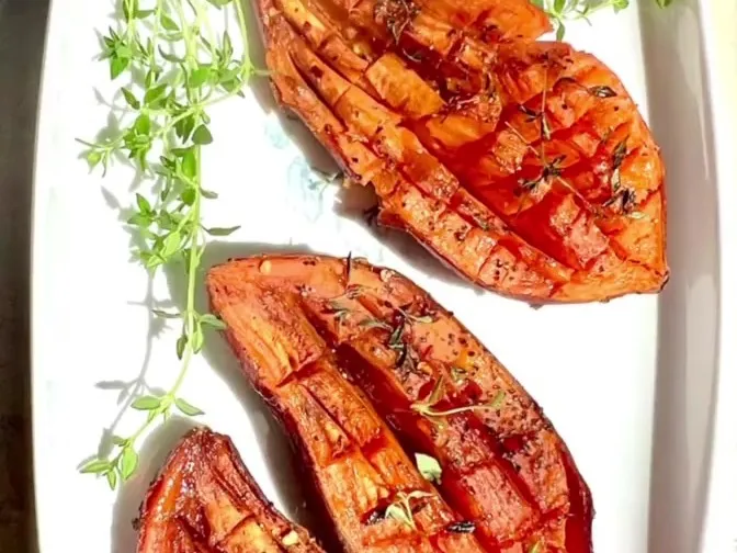 Roasted sweet potato halves scored in a grid pattern, with fresh thyme