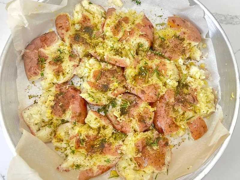 Smashed roasted potatoes topped with za’atar in a round pan