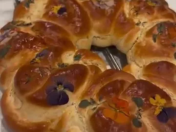 Baked challah ring decorated with pressed edible flowers and herbs
