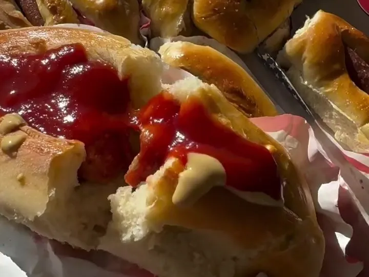 Dough-wrapped hot dogs baked until golden, one held up close