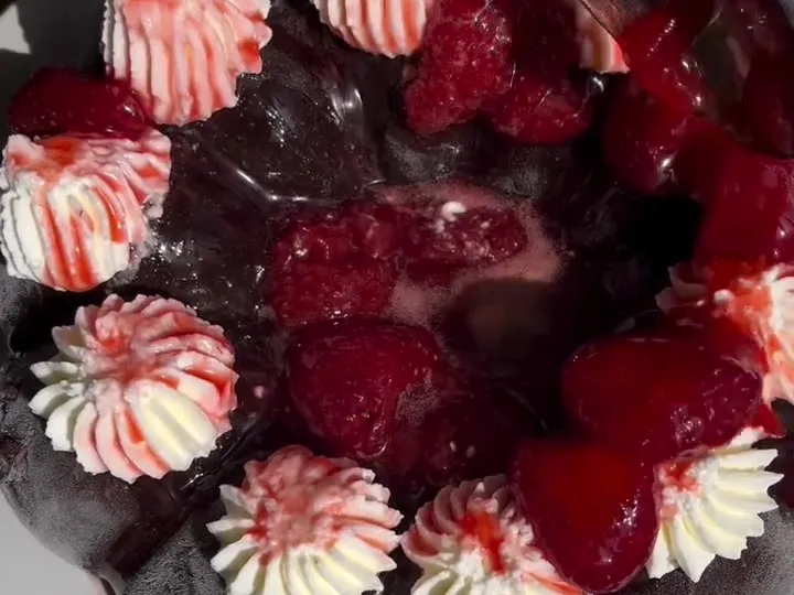 A frozen chocolate banana ring decorated with whipped cream rosettes and strawberries