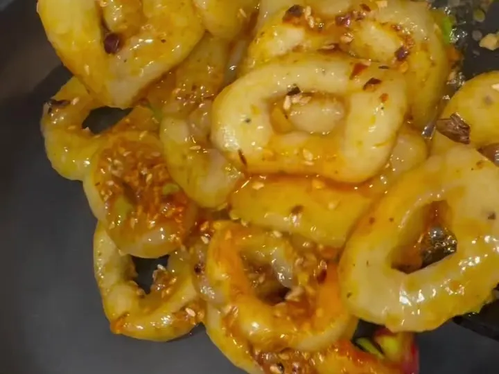Potato rings shaped like calamari, coated in chili oil sauce in a pan