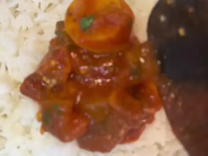 Eggplant and potato goulash in tomato sauce spooned over white rice