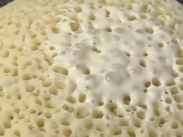 Lachuch flatbread cooking in a pan, covered in bubbles