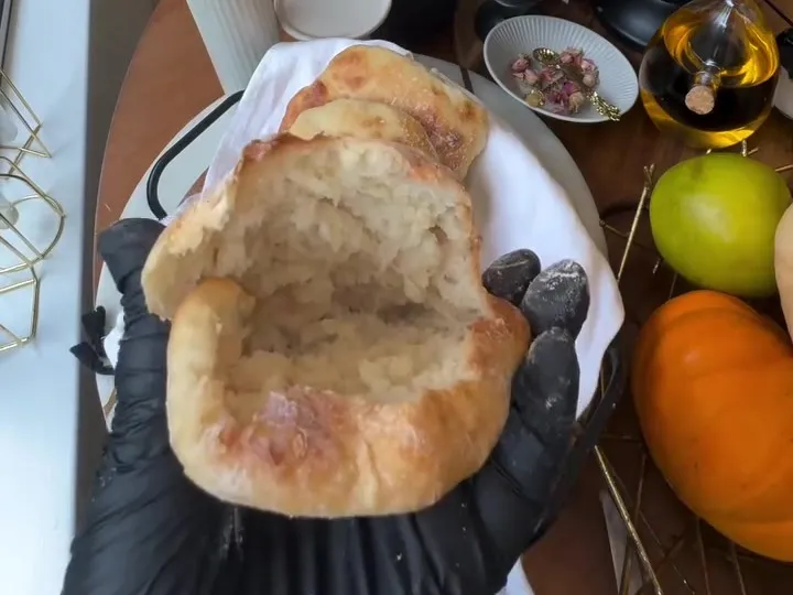 A torn Yemenite pita with a soft, airy crumb held over a basket of pitas